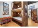 Unique bunk room featuring wood paneled walls, sleeping for eight, ladders for access and adjacent bathroom at 51238 N Pinal Ranch Rd, Miami, AZ 85539