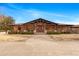 Elegant home boasts a covered porch with stone pillars, manicured landscaping, and a serene desert setting at 51238 N Pinal Ranch Rd, Miami, AZ 85539