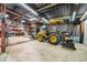 Spacious garage featuring a yellow tractor, shelving units, and ample storage space for equipment at 51238 N Pinal Ranch Rd, Miami, AZ 85539