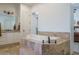 This bathroom has a large soaking tub with a stone surround, a double sink vanity, and a view into the main bedroom at 9612 W Mariposa Grande --, Peoria, AZ 85383