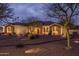 Single-story home with stone facade and desert landscape, enhanced by strategic outdoor lighting at twilight at 9612 W Mariposa Grande --, Peoria, AZ 85383