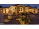 Inviting home showcasing a stone facade, tiled roof, and desert landscaping, illuminated with soft, warm exterior lighting at 9612 W Mariposa Grande --, Peoria, AZ 85383
