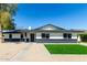 Beautiful single-story home featuring gravel landscaping, lush grass, and a stylish black and white color scheme at 1504 E Jasmine St, Mesa, AZ 85203