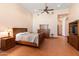 Bedroom with a large window, wooden furniture, terracotta tile floor, and ceiling fan at 16835 E Skinner Dr, Rio Verde, AZ 85263