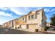 Exterior shot showcasing a row of townhomes with various stucco finishes and attached garages under a blue sky at 1950 N Center St # 111, Mesa, AZ 85201