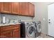 Well-equipped laundry room with granite counters, sink, washer, and dryer and wooden cabinets at 20212 E Appaloosa Dr, Queen Creek, AZ 85142