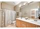 Neutral bathroom with double sinks, a shower with curtains, and wooden cabinets at 22503 N 76Th Pl, Scottsdale, AZ 85255