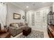 Cozy living room with a comfortable couch, ottoman and stylish rug, with view to adjacent room through french doors at 26231 W Maple Dr, Buckeye, AZ 85396