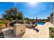 Outdoor kitchen with built-in grill and granite countertops overlooking the pool at 26231 W Maple Dr, Buckeye, AZ 85396