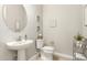 Stylish powder room with pedestal sink, decorative mirror and modern fixtures for guests at 26231 W Maple Dr, Buckeye, AZ 85396