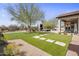 Expansive backyard featuring a putting green, outdoor kitchen, fireplace, and covered patio at 27728 N 68Th Pl, Scottsdale, AZ 85266