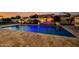 Stunning swimming pool with a water feature illuminated with purple lights surrounded by well-lit plants and patio at 3392 E Gemini Ct, Chandler, AZ 85249