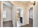 Hallway showcasing a bathroom with glass enclosed shower and a bedroom with shuttered window at 6664 W Rose Garden Ln, Glendale, AZ 85308