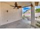 Covered patio featuring a ceiling fan and stucco wall, leading to the paved backyard at 6664 W Rose Garden Ln, Glendale, AZ 85308