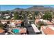 Picturesque aerial view of a community with a pool, palm trees, mountain backdrop, and red-tiled roofs at 10410 N Cave Creek Rd # 1032, Phoenix, AZ 85020