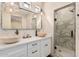 Modern bathroom with double sinks, white cabinets, and a glass-enclosed shower at 12216 S 214Th Ave, Buckeye, AZ 85326