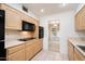 Functional kitchen featuring light wood cabinets and black appliances, with a view to the next room at 14215 N Boswell Blvd, Sun City, AZ 85351