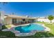 Relaxing pool with sunny skies, surrounded by lush green grass and a covered patio with an outdoor table set at 14433 N 37Th St, Phoenix, AZ 85032