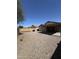 View of the gravel backyard with covered patio, block wall, and desert landscaping at 1606 S 226Th Dr, Buckeye, AZ 85326