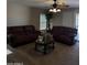 Comfortable living room with a ceiling fan, two brown couches, and a coffee table with photos at 1606 S 226Th Dr, Buckeye, AZ 85326