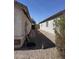 View of the home's side yard, which features desert landscaping, an access gate, and a hose at 1606 S 226Th Dr, Buckeye, AZ 85326