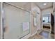 Bathroom featuring frosted glass shower with tiled floors and hallway leading to bedroom at 19437 N Guardian Ln, Surprise, AZ 85387