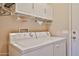 Bright laundry room with white washer, dryer, cabinets, and door at 19437 N Guardian Ln, Surprise, AZ 85387