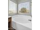 Bright bathroom featuring a soaking tub with tile surround and natural light from large windows at 2015 S 80Th Ln, Phoenix, AZ 85043