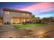 Backyard view with a covered patio, artificial grass, and accent lighting at dusk at 2130 E Knudsen Dr, Phoenix, AZ 85024