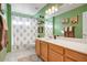 Bright bathroom with green walls featuring tile flooring, a tub/shower combination, and single sink vanity at 2130 E Knudsen Dr, Phoenix, AZ 85024