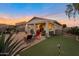 Backyard with putting green, hot tub, covered patio, and comfortable outdoor seating at sunset at 28249 N Shundeen Cir, San Tan Valley, AZ 85143