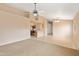 Open-concept living room with neutral carpet, fan, and seamless flow to kitchen at 3151 W Donald Dr, Phoenix, AZ 85027