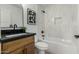 Bathroom featuring a shower-tub combo with white tile and a wooden vanity with black countertop at 331 W Stanford Ave, Gilbert, AZ 85233