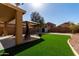 Spacious backyard with artificial grass, stone landscaping and gazebo-covered patio area at 41955 W Hillman Dr, Maricopa, AZ 85138