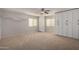 Bright, carpeted bedroom with a ceiling fan, neutral walls, storage cabinets and shelving and large windows at 41955 W Hillman Dr, Maricopa, AZ 85138