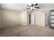 Bedroom featuring a ceiling fan, neutral walls, carpet and views of the adjacent bathroom with a sliding door at 41955 W Hillman Dr, Maricopa, AZ 85138