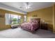 Main bedroom with neutral carpeting, ceiling fan, and a large window overlooking a lush landscape at 42368 W North Star Dr, Maricopa, AZ 85138