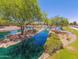 Scenic view of a pond with lush greenery, trees, and a charming waterfall feature, perfect for relaxation at 42368 W North Star Dr, Maricopa, AZ 85138