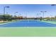 Well-maintained tennis court featuring green and blue surfaces, surrounded by fencing and lush landscaping at 42368 W North Star Dr, Maricopa, AZ 85138