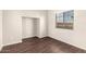 A bright, empty bedroom featuring wood-look floors, a closet nook, and a window with a view at 4675 E Olney Ave, Gilbert, AZ 85234