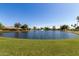 Community pond with fountain and lush green grass, surrounded by single-Gathering homes and trees at 6494 W Matilda Ln, Glendale, AZ 85308