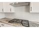 Close-up of a stainless steel stove top, tile backsplash, and granite countertops in a modern kitchen at 7854 W Mockingbird Way, Florence, AZ 85132