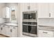 Modern kitchen with built-in microwave, oven, white cabinets and granite countertops and tile backsplash at 7854 W Mockingbird Way, Florence, AZ 85132