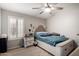 Cozy bedroom features a bed with tufted headboard, ceiling fan, and window with plantation shutters at 7866 W Taro Ln, Glendale, AZ 85308