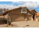 Angle view showcasing the home's side and two-car garage with desert landscaping; partly cloudy skies create a beautiful backdrop at 7866 W Taro Ln, Glendale, AZ 85308