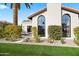 Lovely home showcasing arched windows, landscaped greenery, and an outdoor seating area at 8206 E Del Camino Dr, Scottsdale, AZ 85258