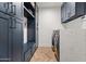 Modern laundry room with blue cabinets, quartz countertop, stainless steel washer and dryer, and beautiful herringbone floors at 8206 E Del Camino Dr, Scottsdale, AZ 85258