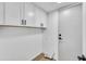 Bright laundry room features upper storage cabinets, white walls, and a sleek white door with black matte hardware at 8840 S 51St St # 2, Phoenix, AZ 85044