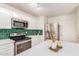 Close up of the kitchen showing the stainless steel appliances and green tile backsplash at 9643 N 81St Dr, Peoria, AZ 85345