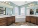 Well-lit bathroom features dual sinks, a soaking tub beneath windows, and stylish tile flooring at 12956 N 152Nd Ave, Surprise, AZ 85379